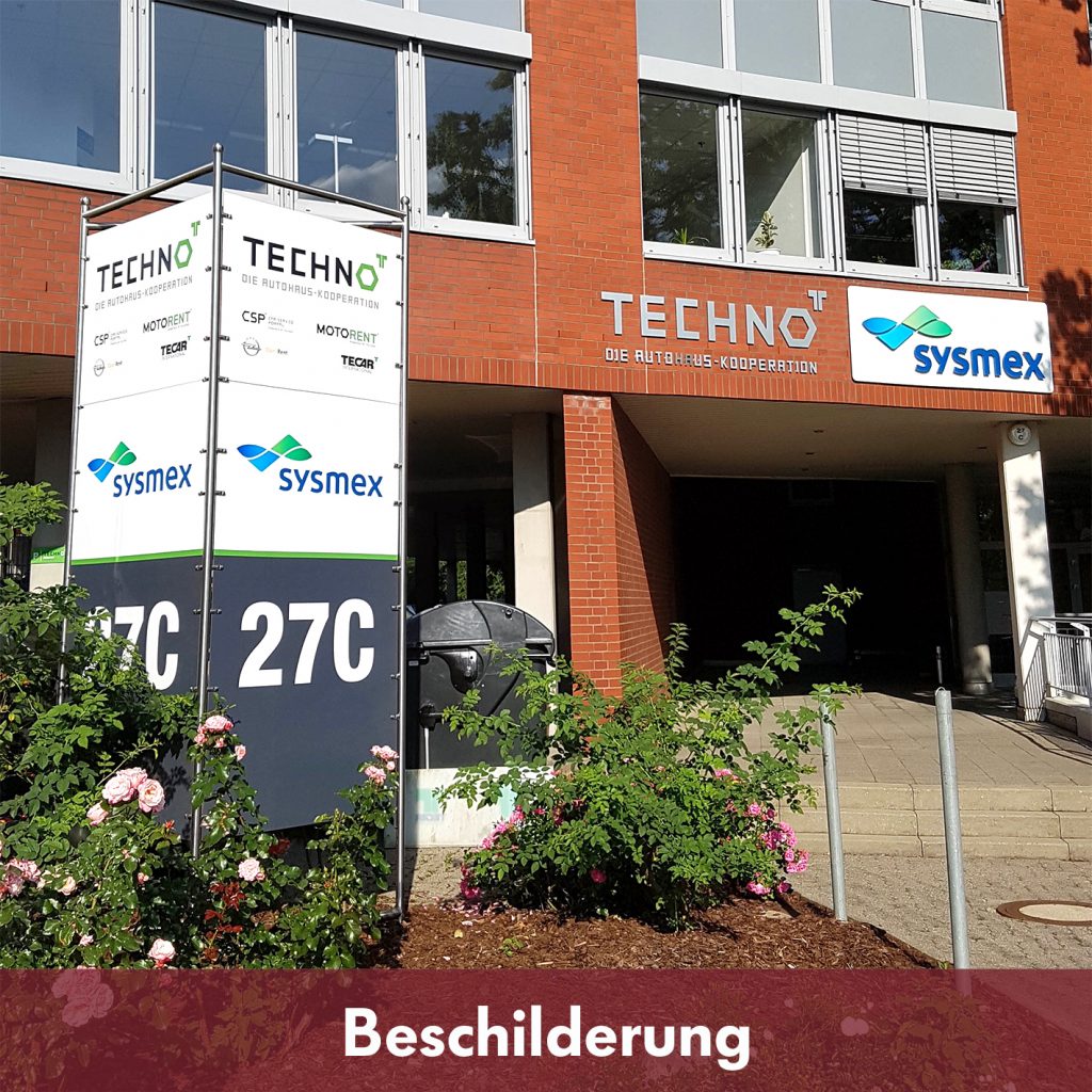 Hauswand mit 3D-Buchstaben, davor ein Pylon